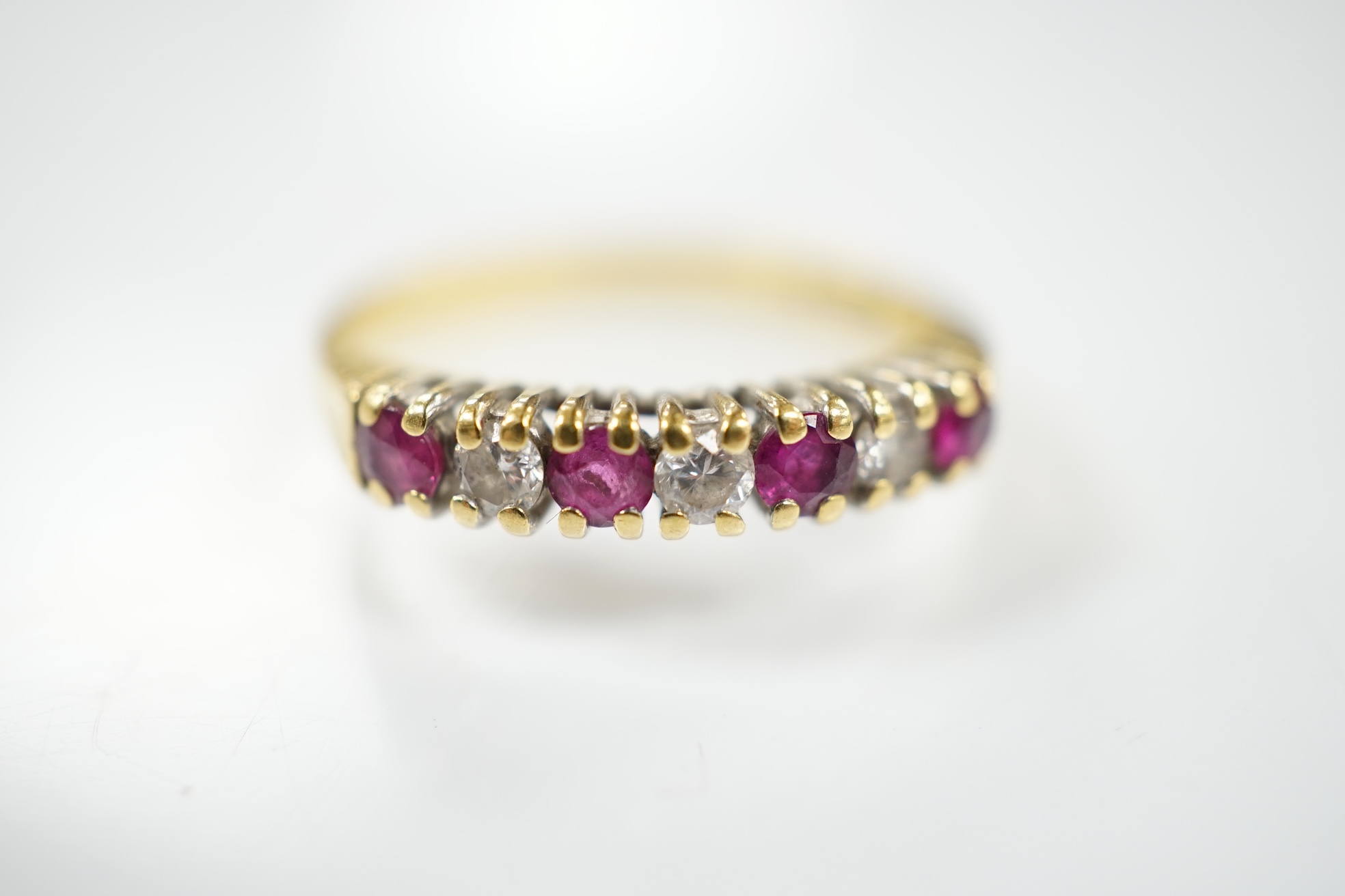 A modern 18ct gold, four stone ruby and three stone diamond set half hoop ring, size P, gross weight 2.8 grams. Condition - fair